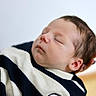newborn, baby, sleeping, infant, face, hand, clothing, striped, closeup, portrait, peaceful, soft_focus, skin, head, person, young_child, indoor, resting, tender, cute