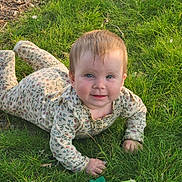 Natalie joined the competition — help win amazing prizes! baby, child, crawling, cute, face, floral_pattern, grass, greenery, hands, happy, head, infant, nature, onesie, outdoor, person, playful, smiling, sunlight, young_child