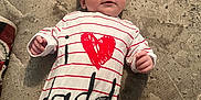 Natalie is registered to the contest to win money with this photo: animal_tail, baby, child, clothing, cute, face, floor, hand, heart, indoors, infant, lying_down, onesie, person, red, striped, text, texture, toy, white