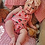 Jolie is registered to the contest to win money with this photo: baby, child, pink_clothing, headband, bow, strawberry_pattern, plush_toy, blanket, knitted_blanket, couch, soft_toy, infant, smiling, cute, indoor, relaxed, skin, foot, hand, person