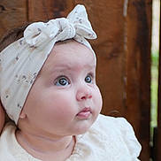 Liv a rejoint le concours — aidez-le/la à gagner de superbes lots ! baby, infant, child, headband, bow, white_clothing, close_up, face, cute, portrait, soft_lighting, indoors, curious, gazing, skin, cheeks, eyes, young, person, headwear