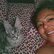 Camila is registered to the contest to win money with this photo: woman, cat, bed, heart_pattern, pillow, smile, fur, indoor, portrait, face, pet, cozy, resting, cute, animal, person, closeup, happy, feline, patterned_bedding