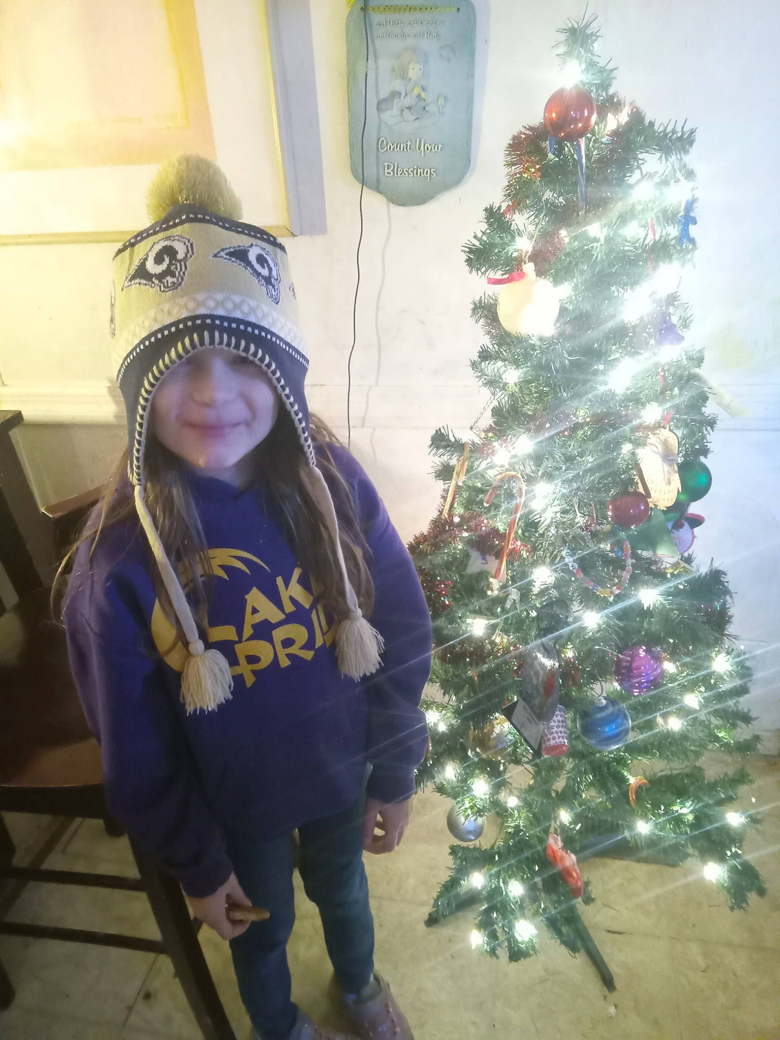 Kenleigh joined the competition — help win amazing prizes! cap, christmas, christmas_decoration, christmas_ornament, christmas_tree, electric_blue, event, evergreen, fun, happy, headwear, holiday, holiday_ornament, joy, ornament, person, plant, room, smile, standing