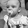 baby, black_and_white, child, closeup, clothing, couch, cushion, cute, expression, eyes, face, hand, indoors, infant, pacifier, person, portrait, shirt, sitting, young