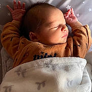 Gabriel participe au concours pour gagner de l'argent avec cette photo : newborn, baby, sleeping, blanket, brown_clothing, star_pattern, infant, cute, peaceful, lying_down, soft_texture, indoors, portrait, human, child, resting, cozy, warm_lighting, small_hands, toddler