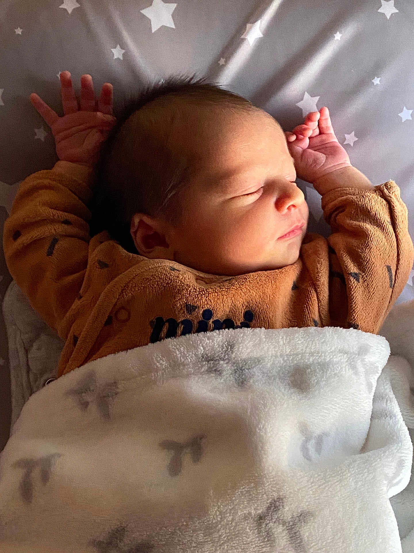 Gabriel participe au concours pour gagner de l'argent avec cette photo : newborn, baby, sleeping, blanket, brown_clothing, star_pattern, infant, cute, peaceful, lying_down, soft_texture, indoors, portrait, human, child, resting, cozy, warm_lighting, small_hands, toddler