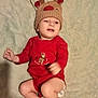 baby, blanket, child, christmas, cute, diaper, festive, happy, holiday, indoors, infant, infant_clothing, lying_down, person, red_onesie, reindeer_hat, smiling, sparkly, winking, winter_hat