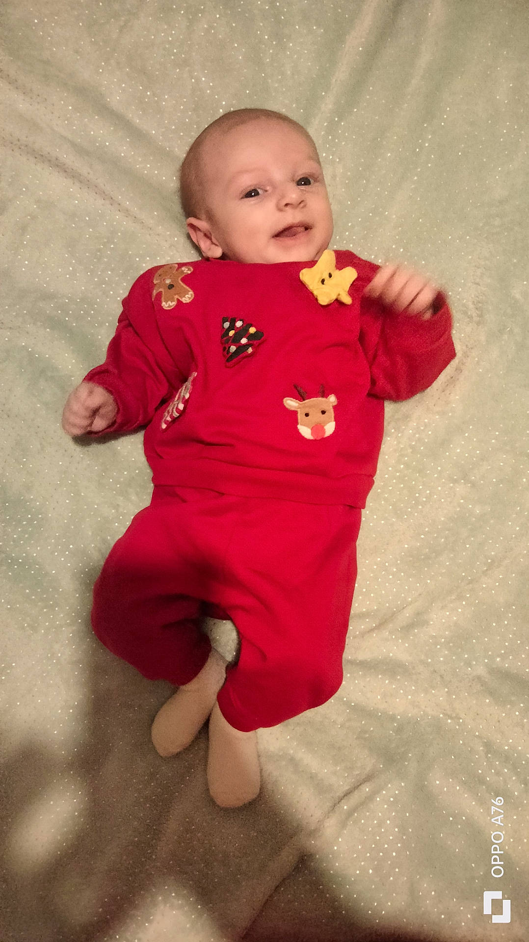 baby, blanket, casual, child, cozy, cute, face, festive, happy, holiday_outfit, indoors, infant, lying_down, person, portrait, red_clothing, small_hand, smiling, soft_texture, young_child