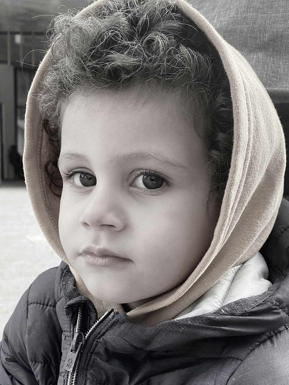 Yahel a rejoint le concours — aidez-le/la à gagner de superbes lots ! child, portrait, black_and_white, curly_hair, hood, jacket, face, expression, young, person, close_up, outdoor, candid, innocence, winter_clothing, eyes, young_child, soft_light, monochrome, serious