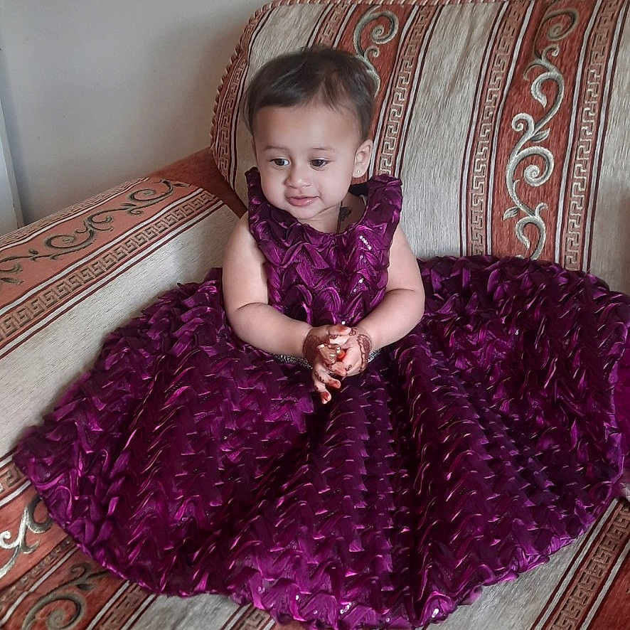 Zehak is registered to the contest to win money with this photo: child, clothing, curious, cute, decor, floor, furniture, henna, indoor, patterned_sofa, person, portrait, purple_dress, sitting, small_child, smiling, sofa, toddler, wooden_floor, young_child