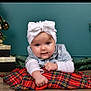 baby, infant, child, white_bow, denim_jacket, plaid_blanket, christmas_tree, gold_baubles, presents, holiday_decor, teal_wall, floor, wooden_floor, posing, cute, portrait, smiling, indoor, festive, cozy