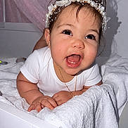 Emily joined the competition — help win amazing prizes! baby, child, toddler, headband, pearl, flower, white_clothing, smiling, happy, towel, bed, indoor, person, cute, portrait, face, skin, hand, decor, star