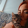 Bozo a rejoint le concours — aidez-le/la à gagner de superbes lots ! person, cat, kitten, tabby_cat, red_hair, hand, cushion, window, indoor, face, pet, animal, cozy, portrait, close_up, patterned_textile, holding, cute, young, casual