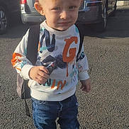 Mao participe au concours pour gagner de l'argent avec cette photo : child, blond_hair, toy_car, sweatshirt, jeans, sneakers, backpack, street, car, building, window, door, pavement, sunlight, shadow, person, outdoor, casual_clothing, young_child, urban