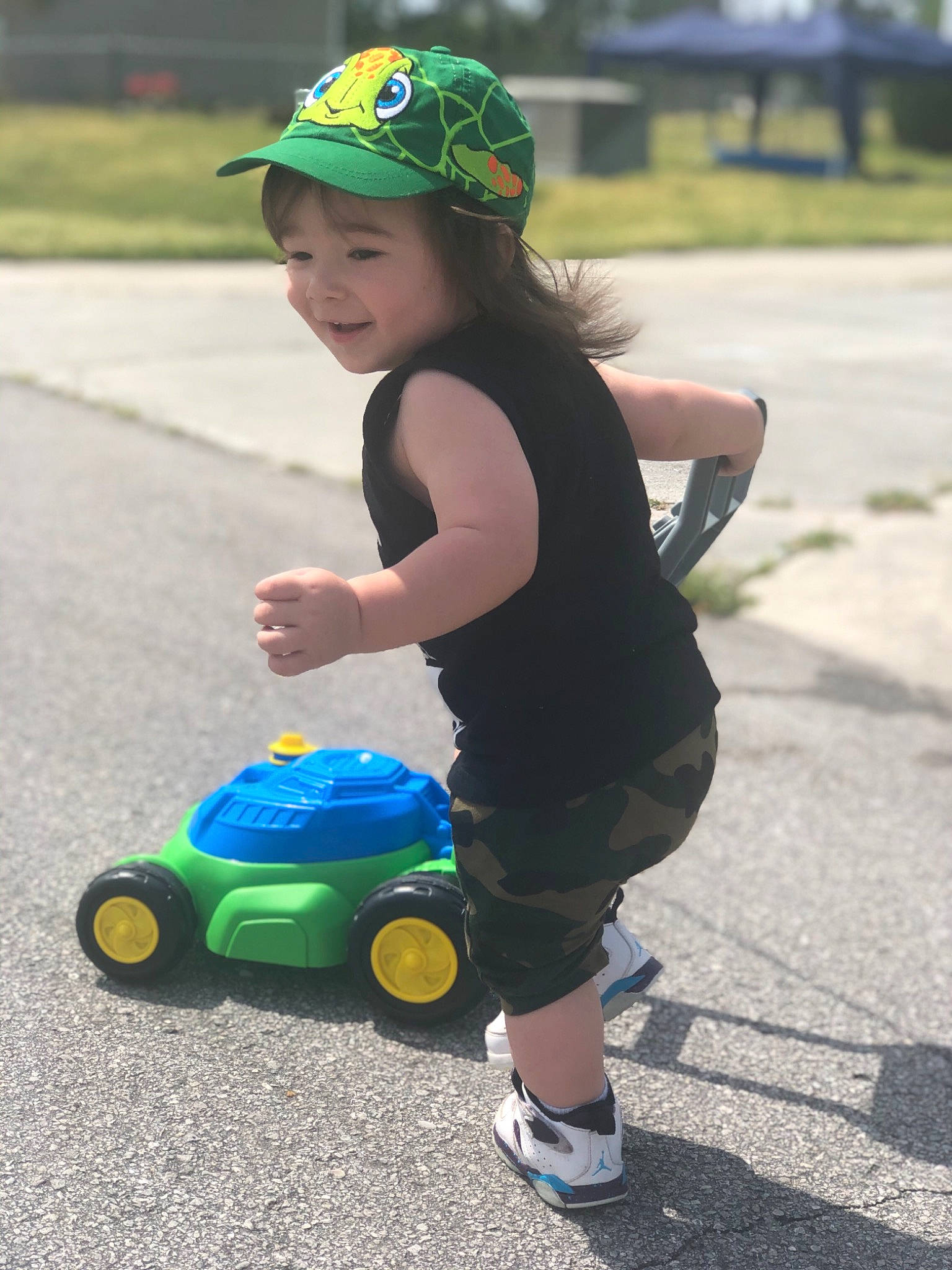 Franklin is registered to the contest to win money with this photo: asphalt, car, child, fun, games, green, headwear, joy, person, personal_protective_equipment, play, recreation, smile, summer, toddler, toy, vacation, vehicle, wheel, yellow