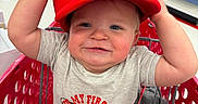 Jackson joined the competition — help win amazing prizes! baby, child, shopping_cart, red_hat, mario_hat, onesie, toy_store, aisle, smiling, cute, face, person, clothing, infant, baby_clothes, shopping, red, cart, indoor, cute_expression