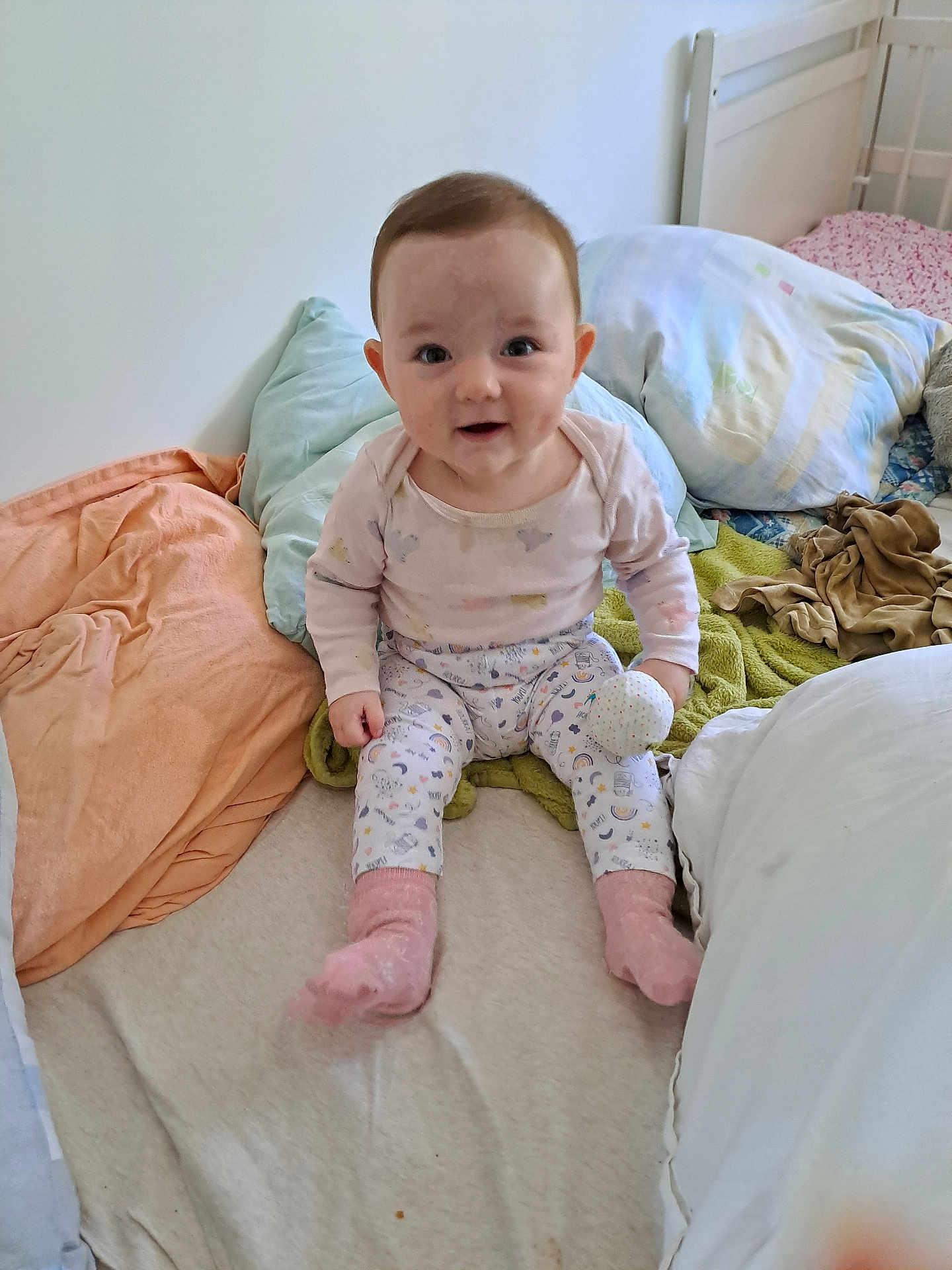 Alizée a rejoint le concours — aidez-le/la à gagner de superbes lots ! baby, child, pajamas, pink_socks, toy_ball, bed, pillow, blanket, indoor, cute, smiling, person, infant, sleeping_area, soft_toys, colorful, cozy, young_child, portrait, home