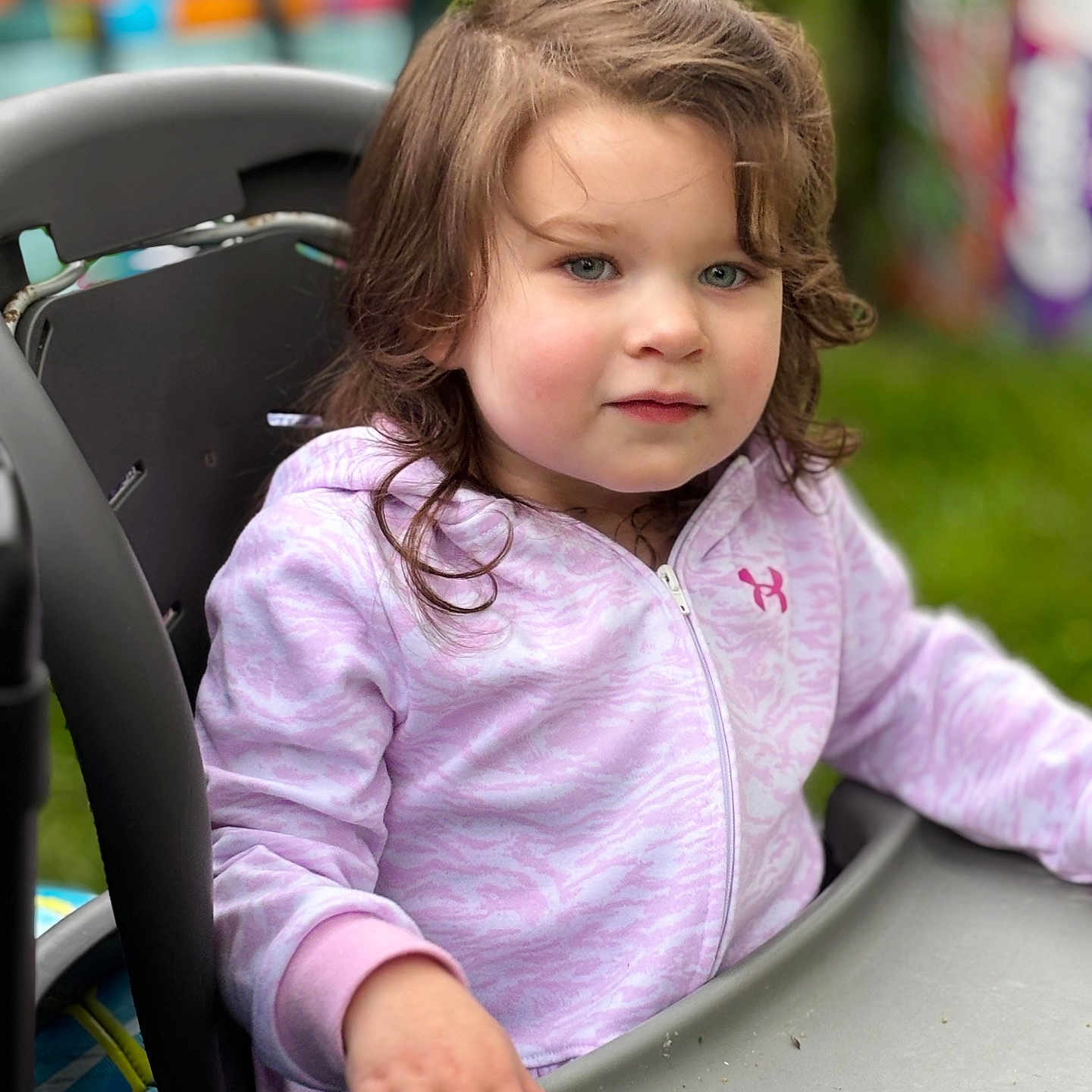 Brynnlee joined the competition — help win amazing prizes! casual_clothing, child, close_up, curly_hair, cute, daylight, expression, face, green_background, hand, high_chair, looking_away, outdoor, person, portrait, purple_hoodie, sitting, soft_lighting, table, young_child