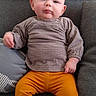 baby, child, clothing, comfortable, couch, cute, face, furniture, head, indoor, infant, pants, person, portrait, sitting, smile, socks, sofa, sweater, young
