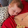 Kaleb is registered to the contest to win money with this photo: baby, child, close_up, comfort, couch, cozy, cute, hair, indoor, infant, necklace, patterned_outfit, peaceful, person, portrait, red_clothing, relaxation, rest, skin, sleeping