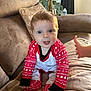 baby, blue_eyes, brown_furniture, child, couch, cozy, cute, hand, holiday_theme, home, indoor, infant, pajamas, plush, portrait, red_clothing, sitting, smiling, sofa, white_clothing