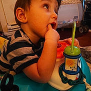 Otis is registered to the contest to win money with this photo: activity_center, baby_toy, bookshelf, carpet, child, curious, expression, face, floor, furniture, hand, head, indoor, person, playtime, room, striped_shirt, stroller, toddler, window