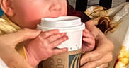 Noah joined the competition — help win amazing prizes! baby, child, infant, portrait, face, eyes, hands, adult, coffee_cup, takeaway_cup, drink_container, blanket, clothing, sitting, indoors, bedroom, home, cozy, close_up, funny