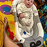 Noah joined the competition — help win amazing prizes! baby, infant, child, bouncer, playroom, activity_mat, colorful, toys, plush_toy, sitting, lying_down, wide_eyed, portrait, indoors, onesie, white_clothing, adult_leg, household, playtime, photography