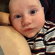 Noah is registered to the contest to win money with this photo: baby, infant, child, portrait, close_up, face, eyes, wide_eyed, looking_at_camera, striped_clothing, pajamas, indoor, cuddling, adult_arm, cozy, soft_lighting, home, photography, adorable, head