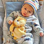Samuel is registered to the contest to win money with this photo: baby, child, hat, plush_toy, lion, cushion, seat, clothing, grey_outfit, patterned_clothing, striped_hat, cute, indoor, infant, toy, comfortable, expression, soft_toy, car_pattern, small_child