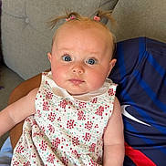 Ambre participe au concours pour gagner de l'argent avec cette photo : baby, child, infant, pigtails, dress, floral_pattern, blue_eyes, face, person, seated, couch, adult, arm, indoor, skin, cute, expression, clothing, comfort, casual