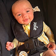 Emerie is registered to the contest to win money with this photo: baby, infant, car_seat, harness, pacifier, yellow_clothing, smile, face, child, safety, seatbelt, cute, young_child, person, apparel, comfort, indoor, closeup, head, hand