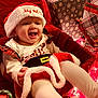 baby, smiling, christmas_hat, holiday_outfit, festive, presents, christmas_lights, red_clothing, white_tights, happy, infant, celebration, holiday, cute, seasonal, indoor, joyful, child, festive_decor, holiday_spirit