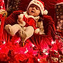 Jaina Willow joined the competition — help win amazing prizes! baby, child, santa_hat, christmas, holiday, red_clothing, lights, ornaments, gift_wrap, festive, decorations, smiling, cute, indoor, celebration, person, cozy, seasonal, plush, happy