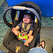 Olivia Grace Cowan is registered to the contest to win money with this photo: baby, car_seat, smiling, foot, toy, indoor, floor_tile, blue_wall, person, jeans, sandals, grin, straps, plastic_toy, child, casual, happy, seat, infant, playful