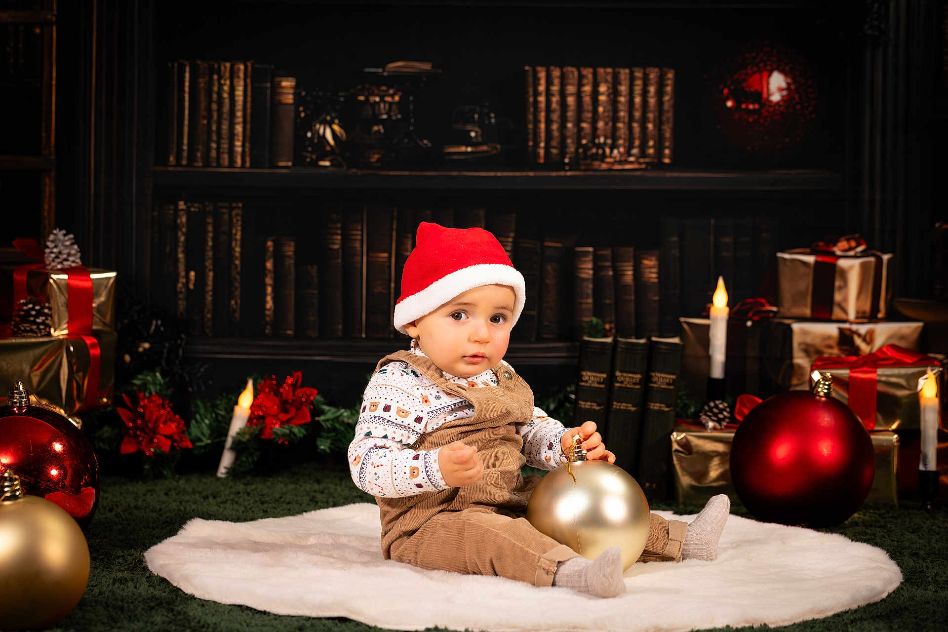 Nathan a rejoint le concours — aidez-le/la à gagner de superbes lots ! baby, child, toddler, santa_hat, christmas_ornament, holiday, festive, overalls, white_rug, candles, gifts, poinsettia, bookshelf, library, decorations, red, gold, indoors, portrait, smiling