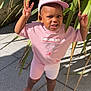 barefoot, cap, casual, child, concrete, gesture, greenery, happy, nike, outdoor, person, pink_clothing, plants, playful, shadow, sidewalk, smiling, sunlight, toddler, young_child
