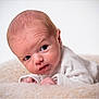 baby, newborn, infant, portrait, face, blanket, studio_photography, closeup, lying_down, white_background, curious, eyes, skin, head, small_hands, cozy, expression, soft_texture, looking_sideways, clothing