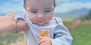 Walker joined the competition — help win amazing prizes! baby, child, flower, hand, outdoor, grass, sky, cloud, person, nature, holding, support, young_child, casual_clothing, greenery, daylight, scenery, portrait, cute, toddler