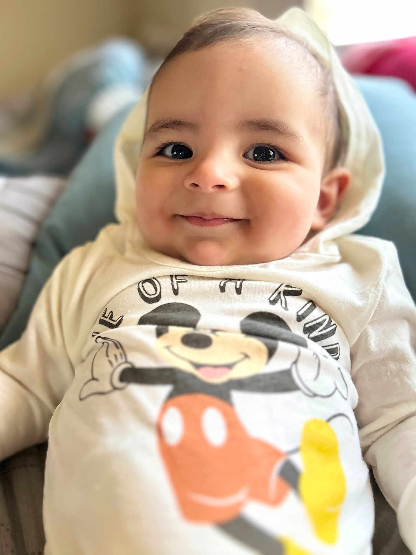 Walker joined the competition — help win amazing prizes! baby, child, smile, hoodie, mickey_mouse, clothing, face, portrait, cute, infant, young_child, person, apparel, happy, indoor, soft_background, close_up, expression, sitting, cozy