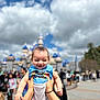Walker joined the competition — help win amazing prizes! baby, child, hands, person, smiling, clothing, mickey_mouse, castle, sky, clouds, outdoor, people, daytime, fun, happy, holding, theme_park, tourist, background, blue
