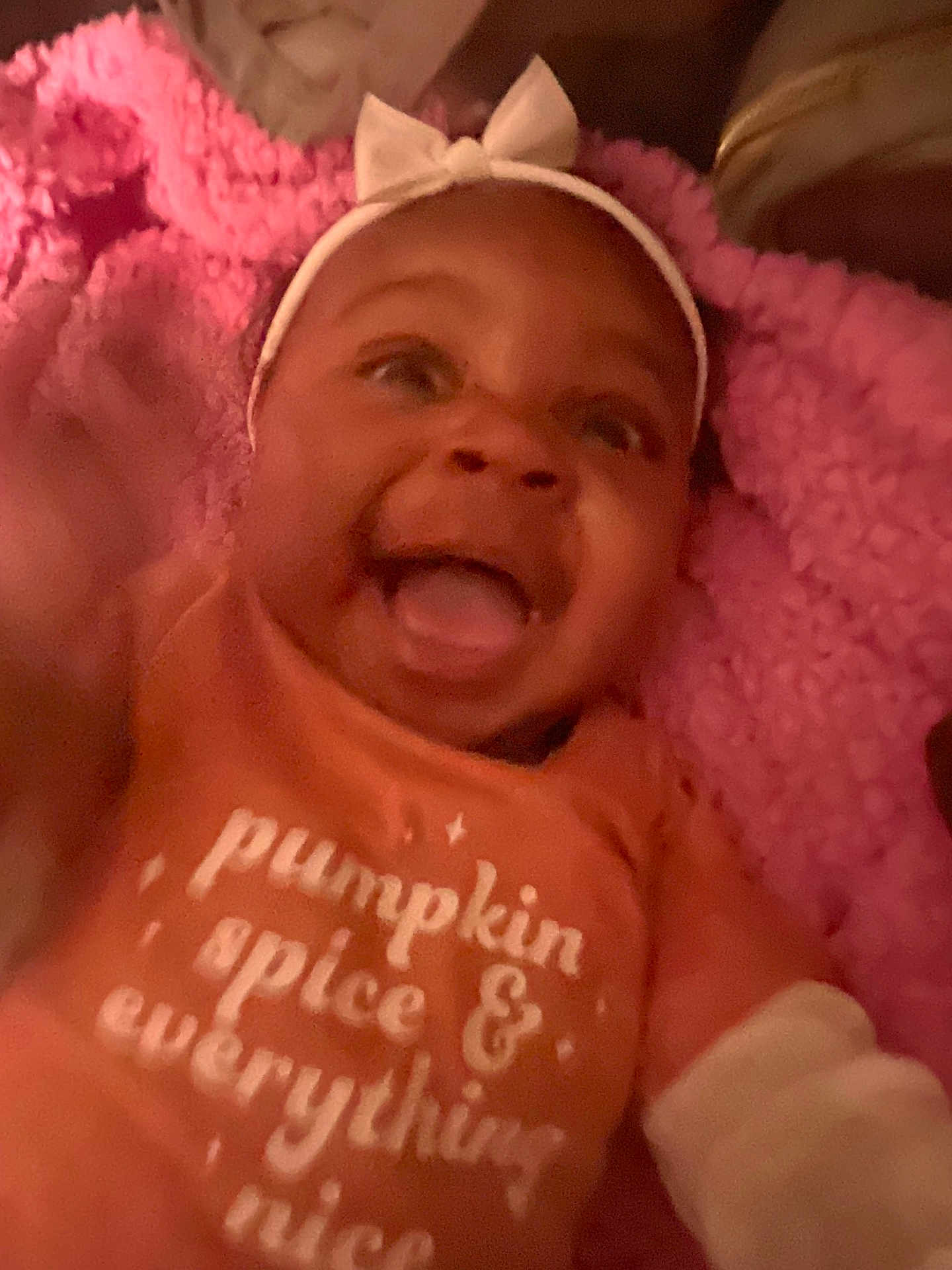Amiria joined the competition — help win amazing prizes! baby, smiling, headband, bow, orange_shirt, text_on_clothing, pink_blanket, happy, infant, closeup, portrait, cozy, cute, child, apparel, fabric, expression, indoor, person, warm