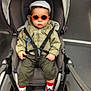 Tiago a rejoint le concours — aidez-le/la à gagner de superbes lots ! toddler, child, sunglasses, cap, stroller, jacket, safety_harness, sneakers, socks, indoor, floor, wheel, person, baby, casual_clothing, transport, cute, fashion, seat, young_child