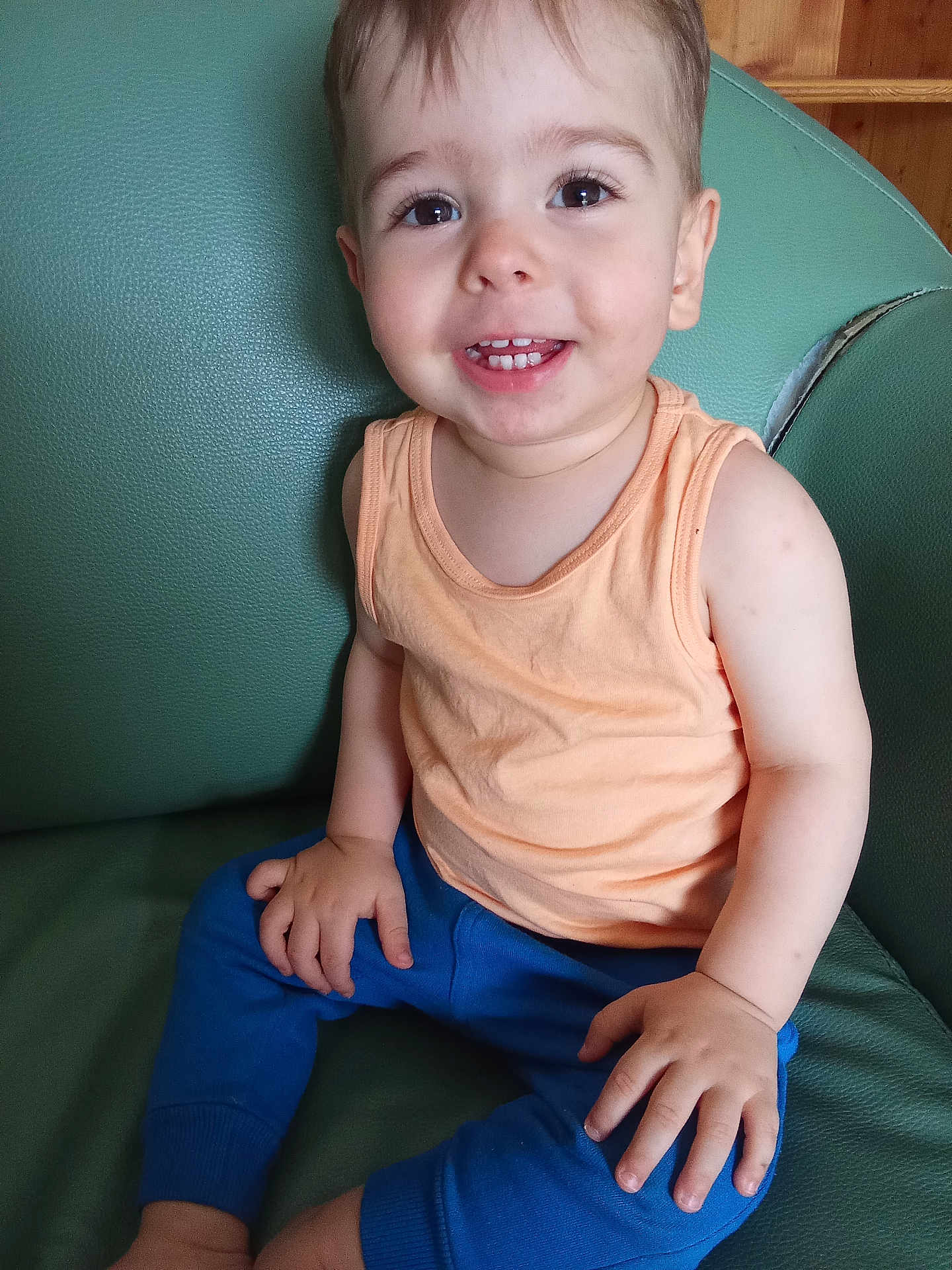 Tiago a rejoint le concours — aidez-le/la à gagner de superbes lots ! toddler, child, smiling, sitting, tank_top, blue_pants, green_chair, indoor, happy, cute, person, skin, face, hand, foot, furniture, casual_clothing, young_child, portrait, baby