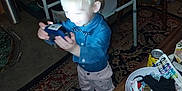 Tanner is registered to the contest to win money with this photo: child, toddler, boy, blue_shirt, bowtie, carpet, indoor, table, chair, toy, smile, person, photo_frame, furniture, carpet_pattern, clutter, bowl, miscellaneous_items, floor, happy