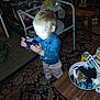 child, toddler, boy, blue_shirt, bowtie, carpet, indoor, table, chair, toy, smile, person, photo_frame, furniture, carpet_pattern, clutter, bowl, miscellaneous_items, floor, happy