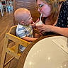 Bjorn is registered to the contest to win money with this photo: adult, baby, casual_clothing, child, curious, drink, family, friendly_interaction, glasses, high_chair, indoor, napkin, restaurant, shared_moment, smile, straw, table, woman, wood_floor, wooden_chair