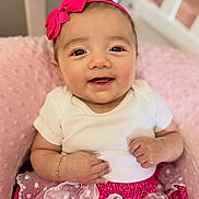 Esther is registered to the contest to win money with this photo: baby, smiling, headband, pink, skirt, polka_dot, white, cushion, sitting, cute, infant, happy, clothing, bracelet, portrait, indoors, soft, child, person, toddler