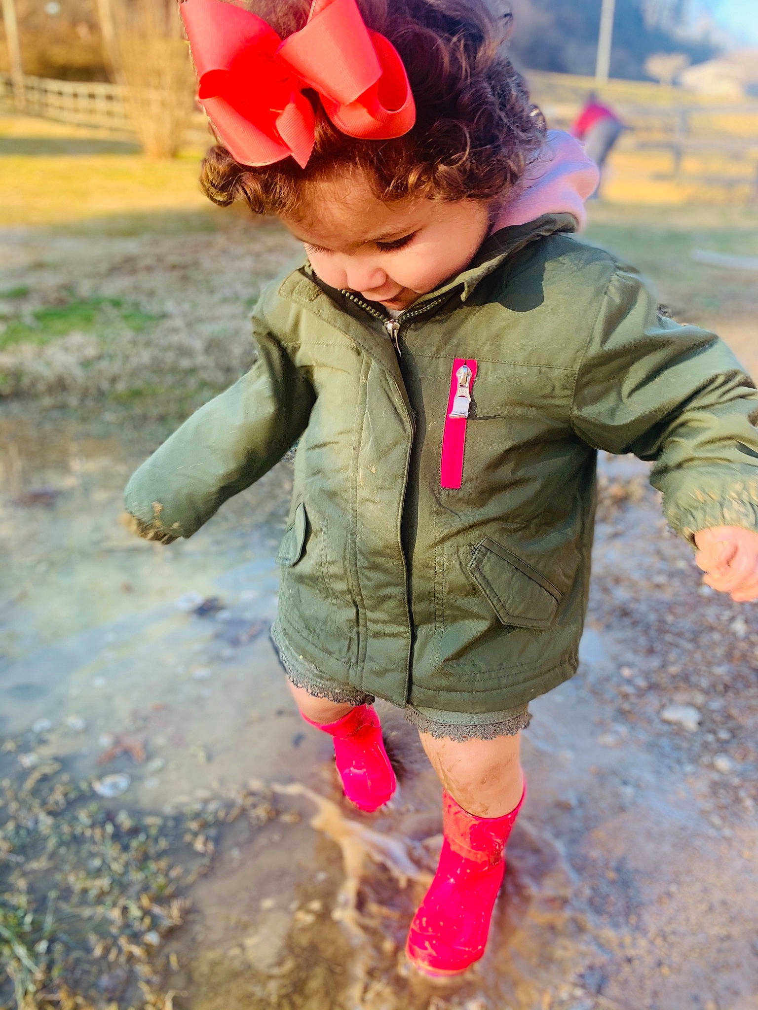 Hadlee is registered to the contest to win money with this photo: cap, child, eye, face, fashion_accessory, fun, grass, happy, head, jacket, mouth, people_in_nature, person, pink, play, puddle, recreation, soil, toddler, water