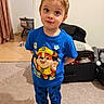 child, indoor, boy, blue_clothing, paw_patrol, standing, curious, playful, carpet, socks, furniture, blanket, curtain, room, toy, face, person, cute, casual, home